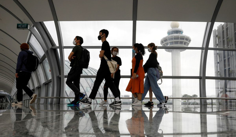 People pass the control tower of Changi Airport